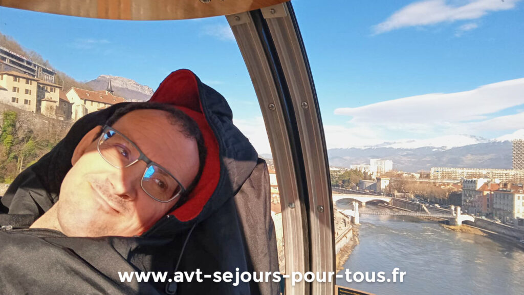 Vacancier en situation de handicap dans une bulle, le téléphérique de Grenoble qui rejoint le Mont Bastille. Visite de la ville organisée par AVT séjours pour tous en Isère lors d'un séjour adapté handicap.