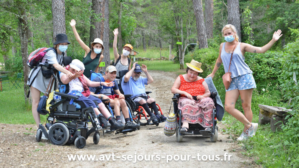 Des vacanciers en fauteuil roulant et leurs animateurs se promènent en pleine nature. Séjour de vacances adaptées organisé par l'association AVT séjours pour tous.