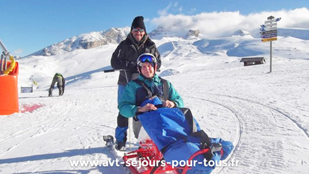 Handiski. Une femme handicapée moteur fait du ski assis avec un moniteur. Activité adaptée PMR proposée lors d'un séjour de vacances adaptées organisé par l'association AVT séjours pour tous.