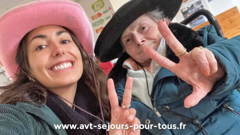 Une personne âgée heureuse avec son auxiliaire de vie pendant un séjour de vacances adaptées à la montagne. Gîte de groupe géré par AVT Séjours pour tous en Isère, dans le Vercors Trièves.